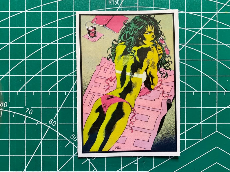 May include: A green comic book character wearing a pink bikini is lying on a pink and white beach towel. The character has green hair and is holding a glass of liquid. The background is a light green and yellow colour.
