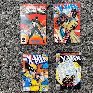 May include: Four comic books featuring X-Men characters. The top left comic book is titled "Marvel Super Heroes Secret Wars". The top right comic book features Wolverine and Jean Grey. The bottom left comic book features Wolverine and other X-Men characters. The bottom right comic book is titled "The Uncanny X-Men".