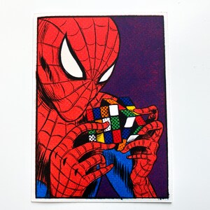 May include: A comic book style illustration of Spider-Man holding a colorful Rubik's Cube in his hands.