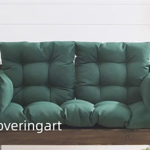 May include: A dark green two-seater bench cushion with a tufted design. The cushion is made of a soft, comfortable fabric and has a wooden frame.