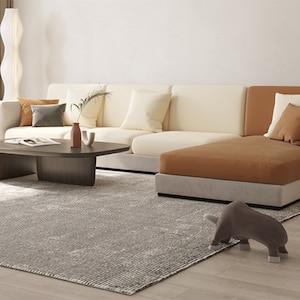 以下が含まれることがあります： クリームとブラウンのファブリック製の大きなコーナーソファがあるモダンなリビングルーム。 ソファにはカウチがあり、木製の天板のコーヒーテーブルの前に置かれています。 グレーのラグが床を覆い、グレーの象の置物がラグの上に置かれています。
