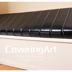 Puede incluir: Un cojín de banco rectangular negro con costuras verticales. El cojín está sobre una base blanca. El texto "CoveringArt" es visible en la base.