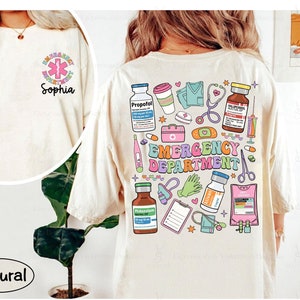 May include: A natural colored t-shirt with a graphic print of medical supplies and the text "Emergency Department".