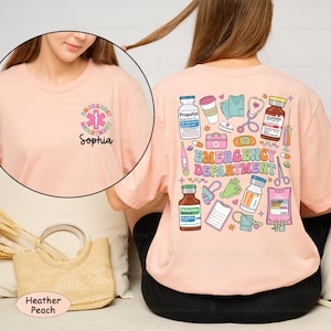 May include: A heather peach t-shirt with a graphic of medical supplies and the text "Emergency Department". The shirt also has a small graphic of a medical symbol and the name "Sophia" on the front.