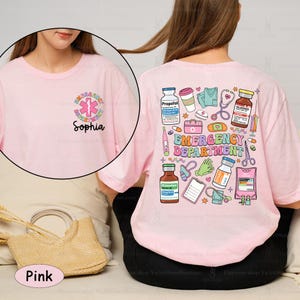 May include: Pink t-shirt with a graphic of medical supplies and the text "Emergency Department" on the back. The front of the shirt has a smaller graphic of a medical symbol and the text "Sophia".