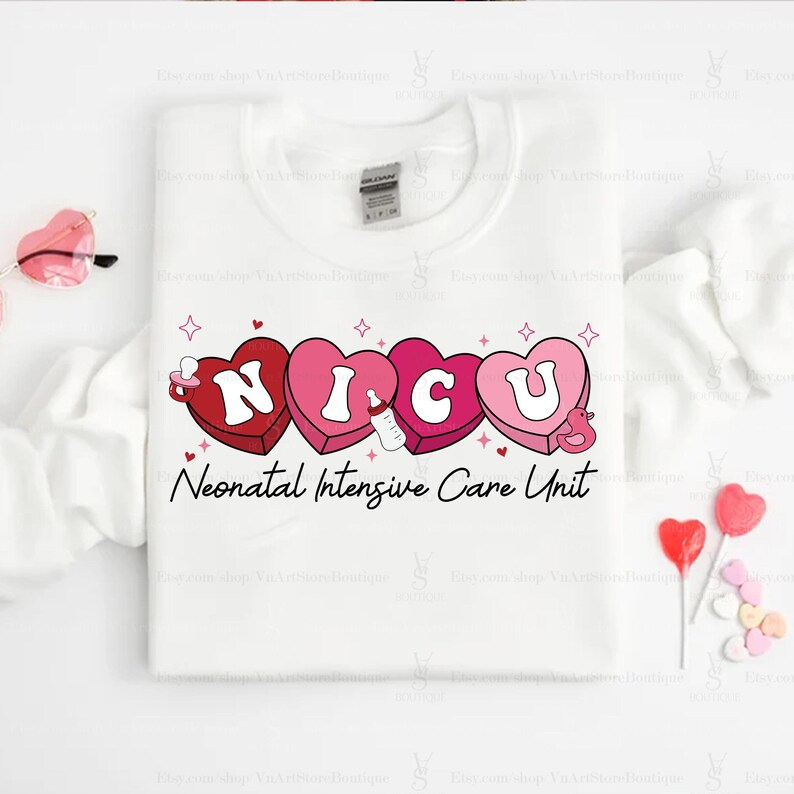 May include: White t-shirt with a pink and red graphic of the word "NICU" in hearts with a baby bottle and a pacifier. The text "Neonatal Intensive Care Unit" is below the graphic.