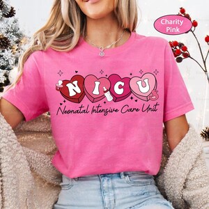 May include: Pink t-shirt with a graphic of the word "NICU" spelled out in hearts with baby-related icons. The text "Neonatal Intensive Care Unit" is below the hearts.
