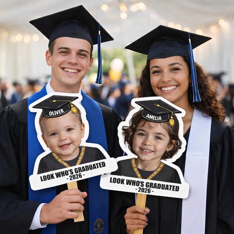Pu&ograve; includere: Due persone in abito da laurea tengono in mano cartelli con la scritta "LOOK WHO'S GRADUATED - 2026". Ogni cartello presenta un ritaglio di un bambino con un cappello di laurea con i nomi "OLIVER" e "AMELIA".