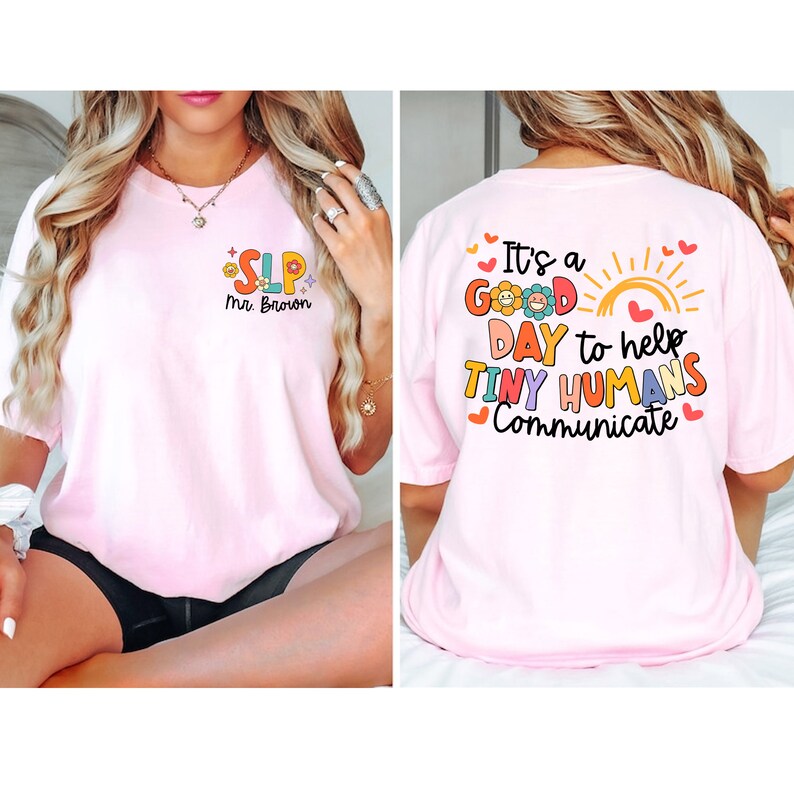 Op de afbeelding: Roze T-shirt met een kleurrijke afbeelding die op de achterkant "It's a good day to help tiny humans communicate" en op de voorkant "SLP Mrs. Brown" zegt.