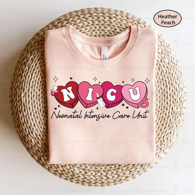 May include: A pink t-shirt with the words "NICU" spelled out in pink hearts with a baby bottle and a duck graphic. The text "Neonatal Intensive Care Unit" is below the hearts.