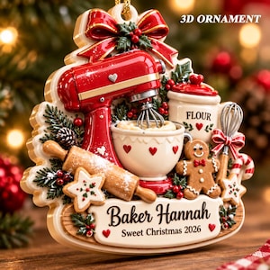 May include: A 3D ornament featuring a red stand mixer, a mixing bowl, a rolling pin, a flour canister, a gingerbread man, and a whisk. The ornament includes the text 3D ORNAMENT, Baker Hannah, and Sweet Christmas 2026, decorated with holly and a red bow.