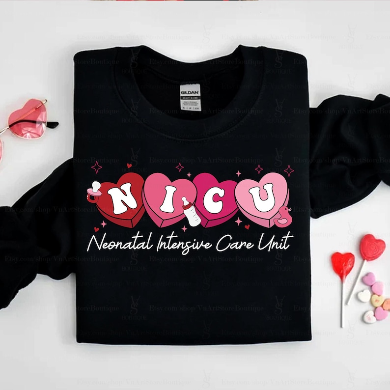 May include: Black t-shirt with a graphic of the word "NICU" spelled out in pink and red hearts. The hearts have a baby bottle, a pacifier, and a duck inside. The text "Neonatal Intensive Care Unit" is below the hearts.