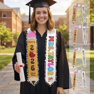 May include: A smiling graduate in a black gown and cap, wearing a personalized graduation sash. The sash features a pencil design with "Class of 2026" and an apple, and another sash with "Mrs. Taylor". Additional sash designs are shown.