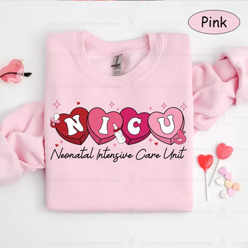 May include: Pink sweatshirt with a graphic of the word "NICU" spelled out in pink hearts with a baby bottle and a pacifier inside each heart. The text "Neonatal Intensive Care Unit" is printed below the hearts.