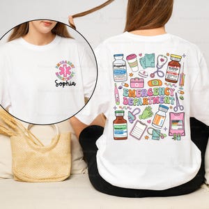May include: White t-shirt with a colorful graphic of medical supplies and the text "Emergency Department". The shirt also has a smaller graphic of a medical symbol and the name "Sophia" on the front.