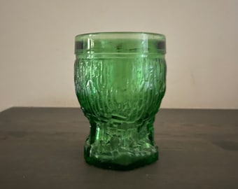 May include: A green glass shot glass with a textured, tree-like design.
