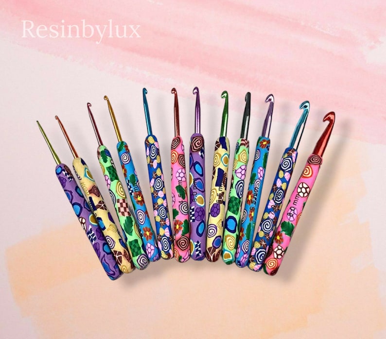 May include: A set of 12 colorful crochet hooks with different sized tips. The hooks are made of metal and have a colorful, patterned plastic handle. The handles are decorated with swirls, flowers, and geometric designs.