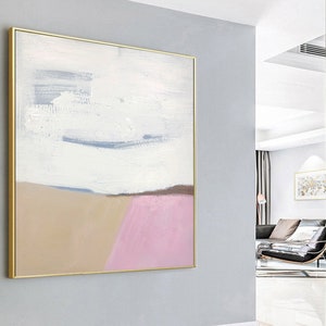 May include: Abstract painting with a gold frame. The painting features a white background with a light blue horizontal line and a brown and pink landscape at the bottom.