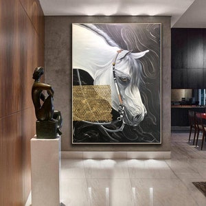 May include: A white horse portrait painting with a gold background. The horse is wearing a bridle and has a black and white striped pattern on its face. The painting is framed and hanging on a wall.