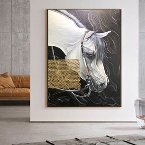 May include: A painting of a white horse with a black background. The horse's head is turned to the side, and its mane is flowing in the wind. The horse is wearing a bridle and a bit. The painting is framed in a gold frame.