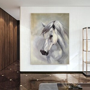 Op de afbeelding: Een schilderij van een wit paardenhoofd met een zachte, wazige achtergrond. Het paard heeft een witte manen en staart, en zijn ogen zijn gesloten. Het schilderij is ingelijst in een eenvoudige, witte lijst.
