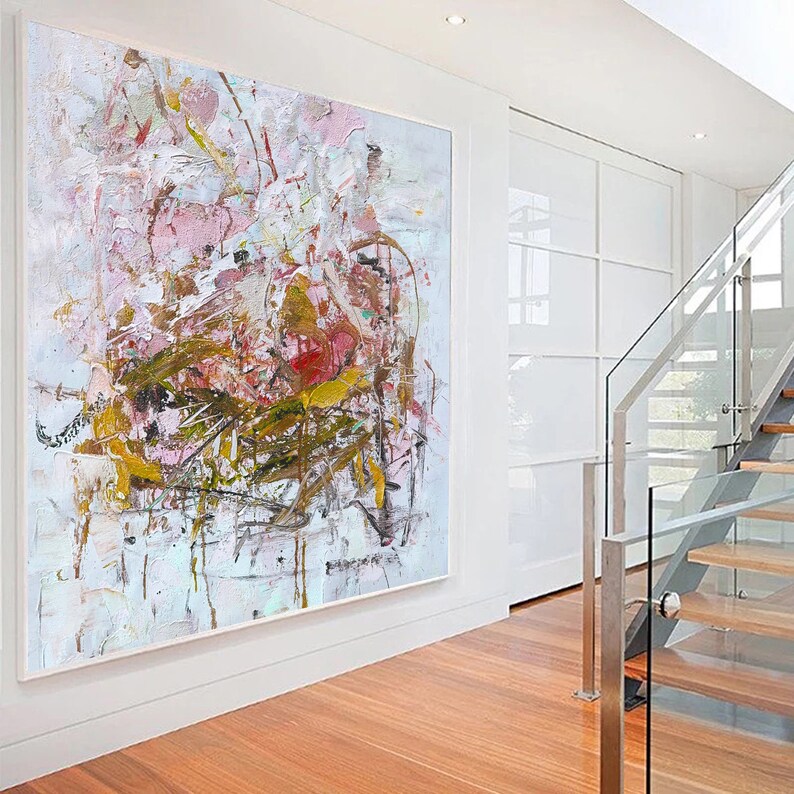 May include: Abstract painting with pink, white, and gold paint splatters and brushstrokes. The painting has a textured surface and is framed in a white frame.