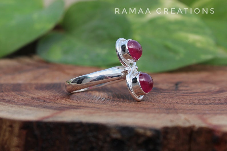 Pu&ograve; includere: Un anello d'argento con due pietre preziose rosse. L'anello &egrave; progettato con una fascia attorcigliata e le pietre preziose sono incastonate in una montatura a  bezel.