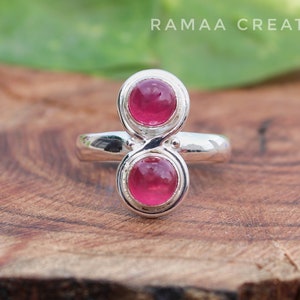 Pu&ograve; includere: Un anello d'argento con due pietre preziose rosa incastonate in un design infinito unico.