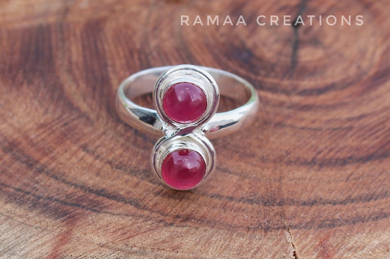 Pu&ograve; includere: Un anello d'argento con due pietre preziose rosa incastonate in un design unico a doppio anello.