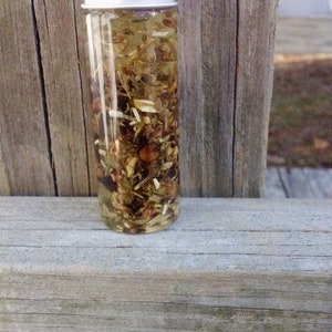 May include: A small glass bottle with a silver lid filled with a clear liquid and various dried herbs and flowers.