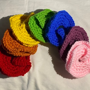 May include: A rainbow of crocheted flower shapes in red, orange, yellow, green, blue, purple, and pink.