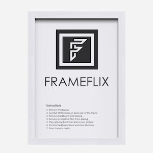 May include: White picture frame with instructions on how to assemble the frame. The instructions include removing packaging, lifting tabs, removing the backboard and glazing, removing protective film, placing the picture, putting the backboard back, and closing the tabs. The frame is ready.
