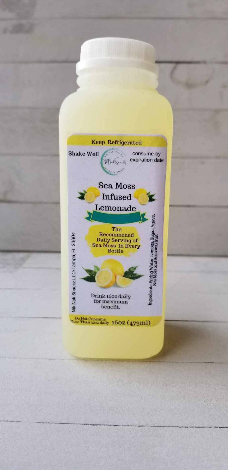 May include: A yellow plastic bottle of Sea Moss Infused Lemonade with a white label. The label says "Keep Refrigerated", "Shake Well", "consume by expiration date", "Sea Moss Infused Lemonade", "The Recommended Daily Serving of Sea Moss In Every Bottle", "Drink 16oz daily for maximum benefit", "Do Not Consume More Than 32oz daily", "16oz (473ml)", and "Ingredients: Spring Water, Lemons, Sugar, Agave, Sea Moss and Seasonal fruit".
