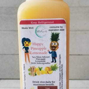 May include: A 16oz bottle of Happy Pineapple Lemonade with a yellow label featuring a cartoon pineapple and a woman. The label says "Sea Moss Infused Pineapple Lemonade with Ashwagandha".