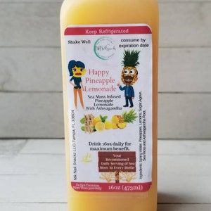 May include: A 473ml bottle of Happy Pineapple Lemonade with a yellow label featuring a cartoon pineapple and a woman. The label reads "Sea Moss Infused Pineapple Lemonade with Ashwagandha".