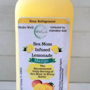 May include: A yellow plastic bottle of mango sea moss infused lemonade. The label reads "Nik Nak Snackz LLC, Tampa, FL 33604", "Keep Refrigerated", "Shake Well", "consume by expiration date", "Sea Moss Infused Lemonade Mango", "The Recommended Daily Serving of Sea Moss In Every Bottle", "Ingredients: Spring Water, Lemons, Sugar, Agave, Sea Moss and Seasonal Fruit", "Drink 160z daily for maximum benefit", "Do Not Consume More Than 320z daily", "16oz (473ml)".