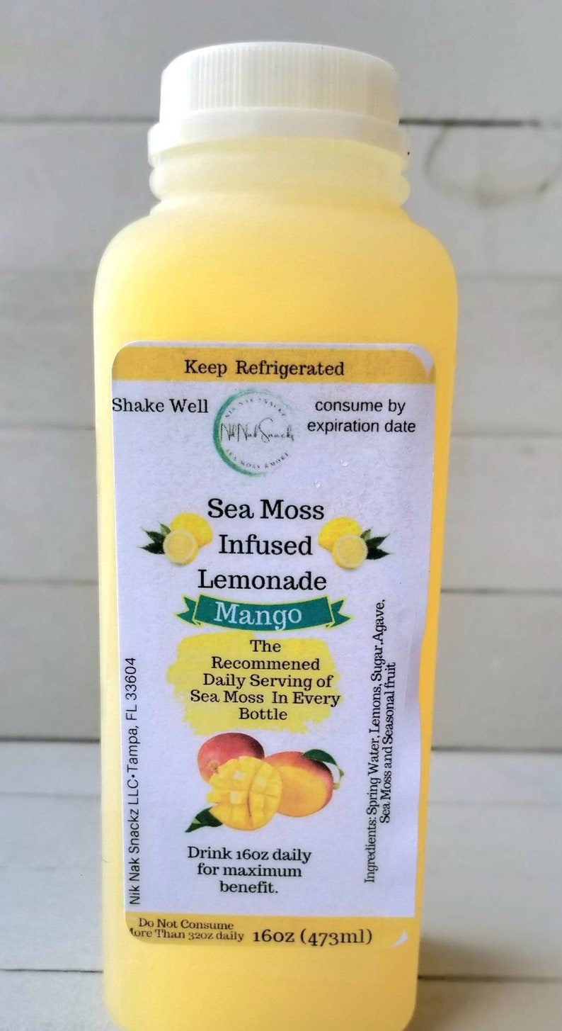 May include: A yellow plastic bottle of mango sea moss infused lemonade. The label reads "Nik Nak Snackz LLC, Tampa, FL 33604", "Keep Refrigerated", "Shake Well", "consume by expiration date", "Sea Moss Infused Lemonade Mango", "The Recommended Daily Serving of Sea Moss In Every Bottle", "Ingredients: Spring Water, Lemons, Sugar, Agave, Sea Moss and Seasonal Fruit", "Drink 160z daily for maximum benefit", "Do Not Consume More Than 320z daily", "16oz (473ml)".
