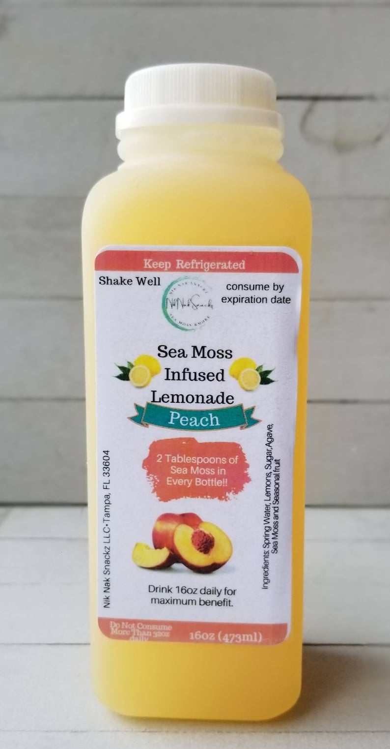 May include: A clear plastic bottle of peach-flavored sea moss infused lemonade. The label reads "Sea Moss Infused Lemonade Peach" and "16oz (473ml)".