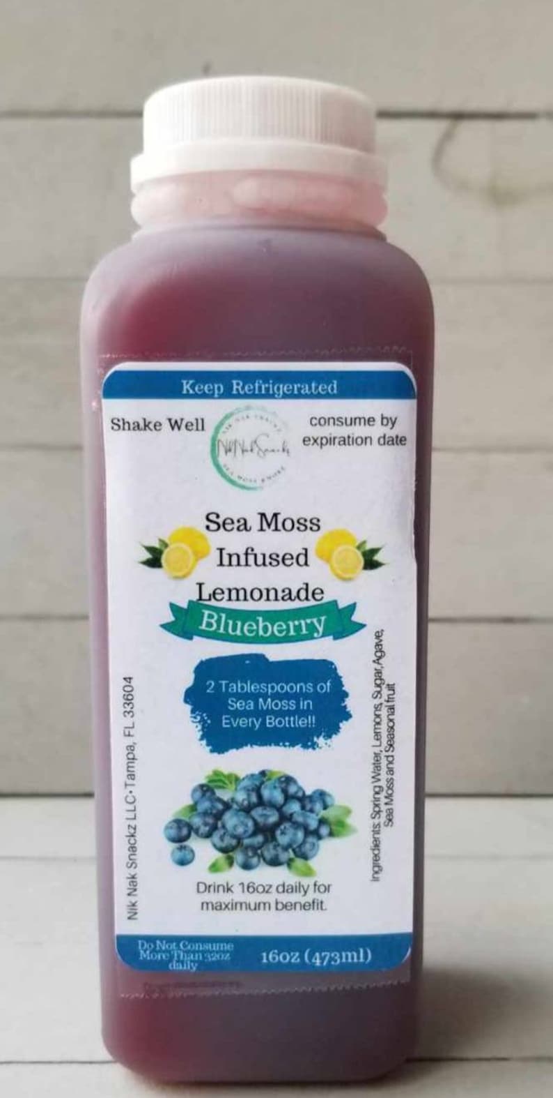 May include: A 16-ounce bottle of blueberry sea moss infused lemonade. The bottle has a white label with the text "Sea Moss Infused Lemonade Blueberry" and "2 Tablespoons of Sea Moss in Every Bottle!!". The label also includes instructions to drink 16 ounces daily for maximum benefit.