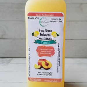 May include: A 473ml bottle of peach-flavoured sea moss infused lemonade. The label is white with a red border and features a peach slice and two lemons. The text on the label reads "Sea Moss Infused Lemonade Peach" and "2 Tablespoons of Sea Moss in Every Bottle!"