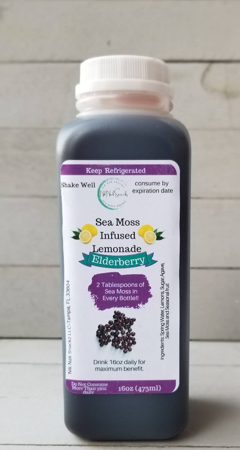 May include: A clear glass bottle with a white lid filled with a dark liquid. The label reads "Sea Moss Infused Lemonade Elderberry" and includes instructions to "Keep Refrigerated" and "Shake Well". The label also states that the product contains 2 tablespoons of sea moss per bottle and that the recommended daily serving is 16 ounces.