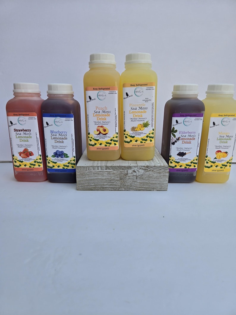 May include: Six glass bottles of sea moss lemonade drink in various flavours: strawberry, blueberry, peach, pineapple, elderberry, and mango. Each bottle has a label with the flavour and the words "Sea Moss Lemonade Drink".