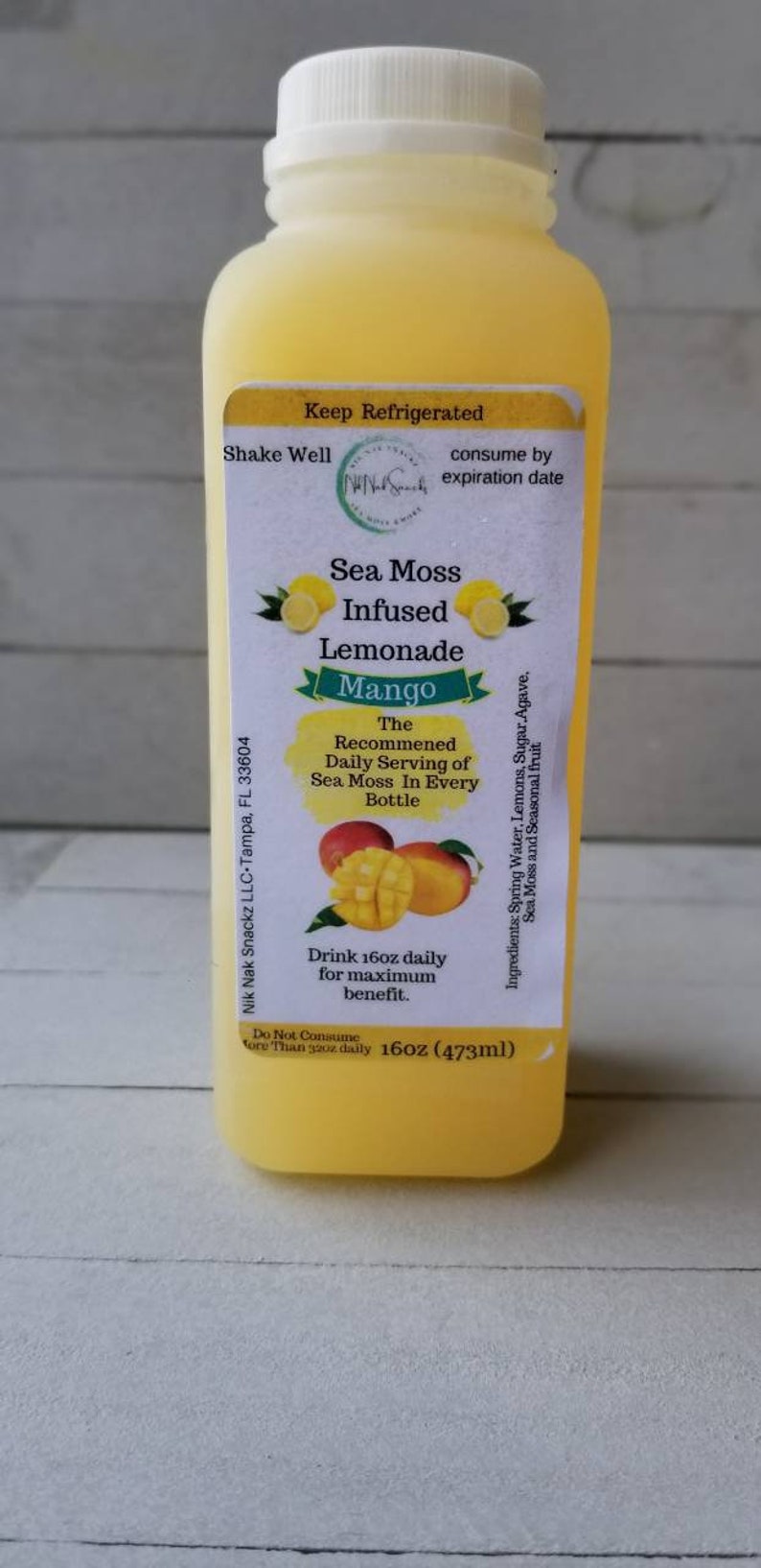 May include: A yellow bottle of Sea Moss Infused Lemonade with Mango flavour. The bottle is labelled with the text "Sea Moss Infused Lemonade Mango" and "The Recommended Daily Serving of Sea Moss In Every Bottle". The bottle is 16oz (473ml).