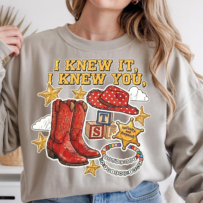 I Knew It I Knew You PNG sublimation design featuring TS5 western cowboy
boots, Jessie hat, gold sheriff badge and friendship bracelet on brown tee