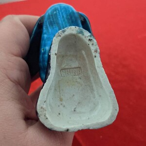 May include: A blue and white ceramic figurine of a person wearing a blue robe. The figurine is marked "CHINA" on the bottom.