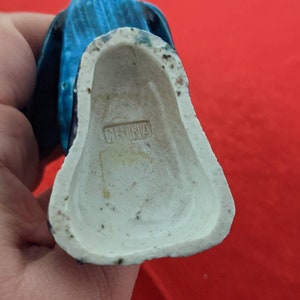 May include: A blue and white ceramic figurine with a white base marked "CHINA".