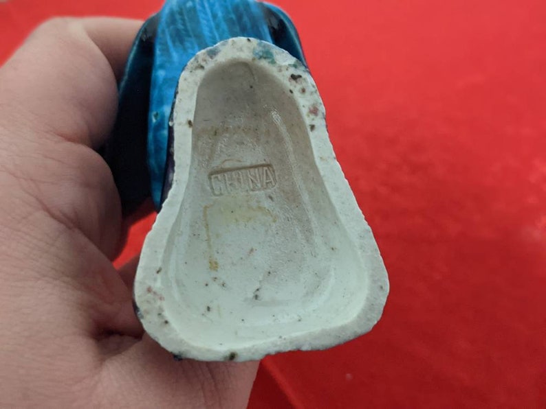 May include: A blue and white ceramic figurine with a white base marked "CHINA".