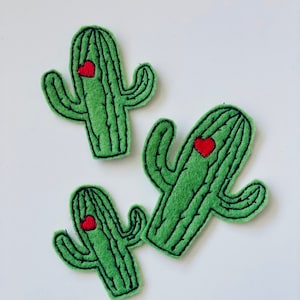 May include: Three green felt cactus patches with red embroidered hearts. The cactus patches are perfect for adding a touch of whimsy to any project.