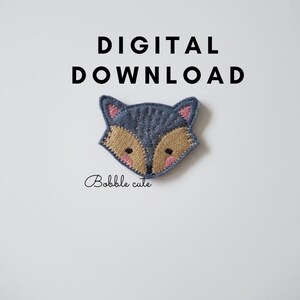 May include: A felt fox applique with a blue-gray body, tan face, and pink accents. The text "DIGITAL DOWNLOAD" is above the fox, and "Bobble cute" is written below. This item is a digital download.