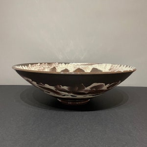 May include: A large, brown ceramic bowl with white marbling. The bowl has a wide, rounded base and a slightly flared rim.